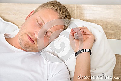 Man wearing smart wristband while sleeping Stock Photo