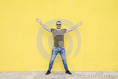 Man wearing sunglasses and posing against a yellow wall Stock Photo