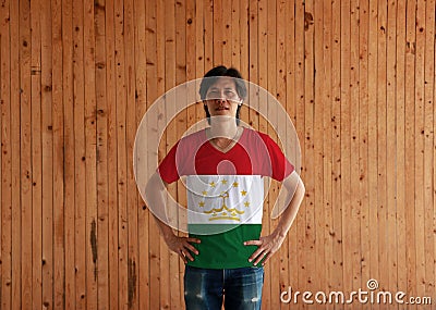 Man wearing Tajikistan flag color shirt and standing with akimbo on the wooden wall background Stock Photo