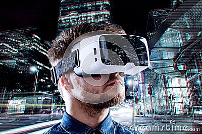 Man wearing virtual reality goggles against night city Stock Photo