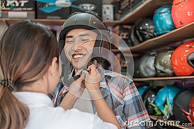 Man wears a helmet with the help of a shop assistant when attaching the strap buckle Stock Photo