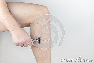 A man on a white background shaves his legs. Hairy legs and care for them. Gender equality concept. A close-up showing the foam, Stock Photo