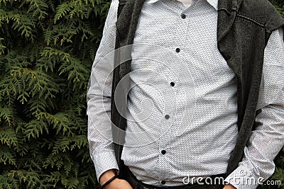 A man in a white polka dot shirt against a background of tuja Stock Photo