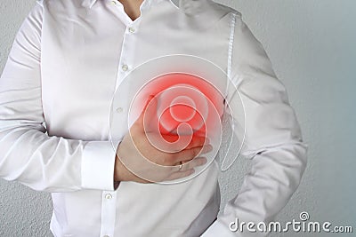 Man in a white shirt holds on to the chest in the heart, a red circle, a symbol of throbbing pain, concept of problems, pain, Stock Photo
