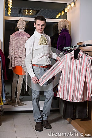 A man in a white shirt with jabot chooses clothes Stock Photo
