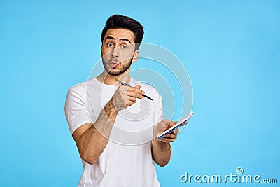 man in white t-shirt notebook with pen student blue background Stock Photo