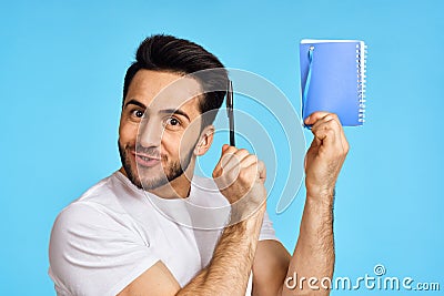man in white t-shirt notebook with pen student blue background Stock Photo