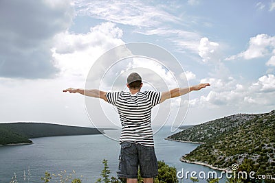 Man who spreads his hands towards the sea and admires the view Stock Photo