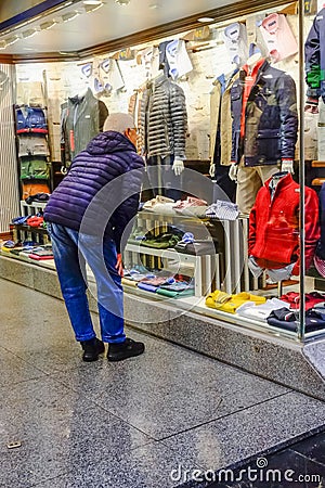 Man window shopping at jackets during heavy rain from Storm Aline in Madrid Spain Editorial Stock Photo