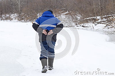 The man in the winter goes and holds on to his back Stock Photo
