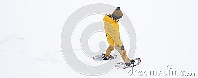 A man in winter, yellow clothes walking on white snow in snowshoes in the distance, there is a place for the inscription Stock Photo
