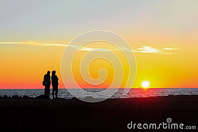 Man and woman admire the colorful sunset on the beach Stock Photo