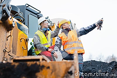 Man and woman as workers on excavator in quarry Stock Photo