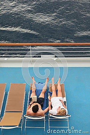 Man and woman both relaxing on chaise longues Stock Photo