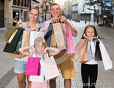 Man and woman with children holding shopping bags in city Stock Photo