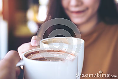 Man and woman clink coffee mugs in cafe Stock Photo