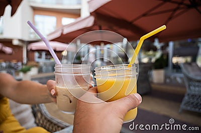 A man and a woman clink glasses of soft drinks in an outdoor cafe. Close-up of hands of a couple on a date Stock Photo