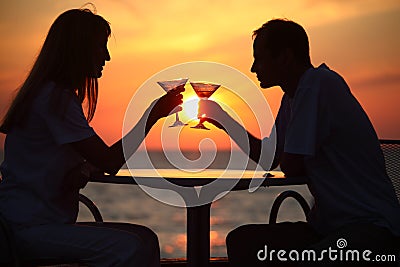 Man and woman clink glasses on sunset outside Stock Photo