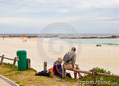 Man and woman conversing by wooden railing near the beach. Editorial Stock Photo