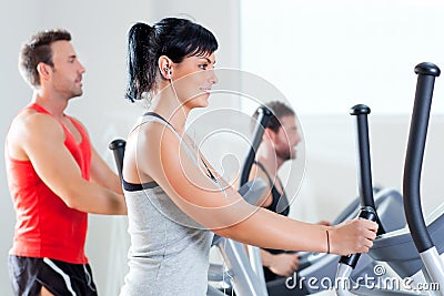 Man and woman with elliptical cross trainer at gym Stock Photo