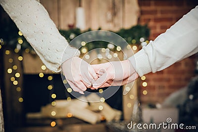 A man and a woman hold hands close-up on the background of blurry lights. Stock Photo