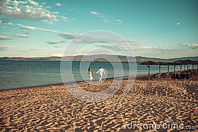 Man and woman hold hands, couple happy on vacation. Couple in love stand on beach, seashore. Honeymoon, just married Stock Photo