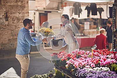 Man and woman holding together bouquet of flowers at bazaar in italy. giving and receiving concept Stock Photo