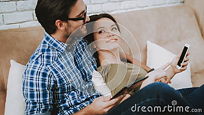 Man Hugs Woman with Smartphone in Hands at Home. Stock Photo