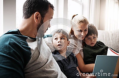 Man, woman and kids on sofa with book learning to read at storytelling time in living room of home. Love, family and Stock Photo
