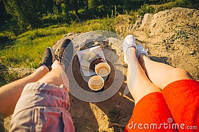 Man and woman legs on the top of the hill with two cups and chocolate Stock Photo