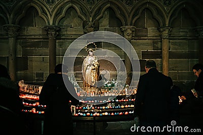 Man and woman light candles in Cathedral Notre-Dame with mary St Editorial Stock Photo