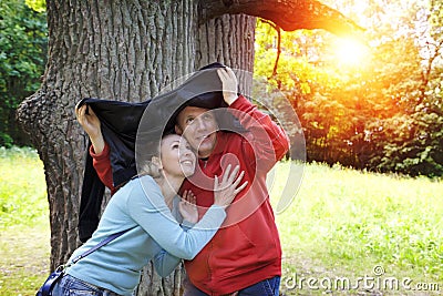 Man and the woman near an oak hide from a rain in the summer day Stock Photo