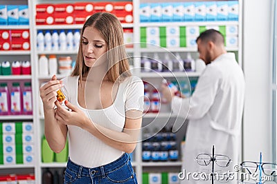 Man and woman pharmacist and client smiling confident holding pills bottle at pharmacy Stock Photo