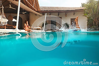 Man And Woman At Pool. Couple In Love Enjoying Summer Vacation At Tropical Villa. Male Diving In Water From Poolside. Stock Photo
