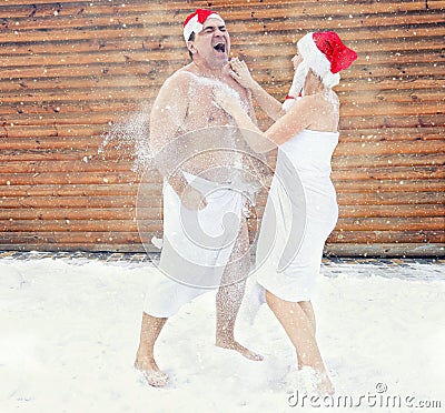 Man and woman refresh in snow after hot sauna.Concept of: relax, vacation,healthy lifestyle. Stock Photo