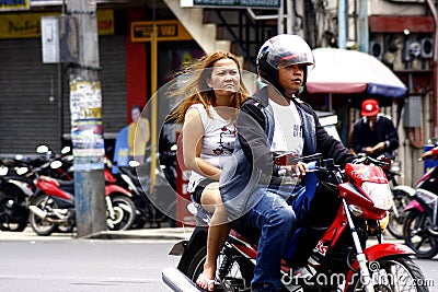 A man and a woman riding in tandem on a motorcycle in Antipolo City. Editorial Stock Photo