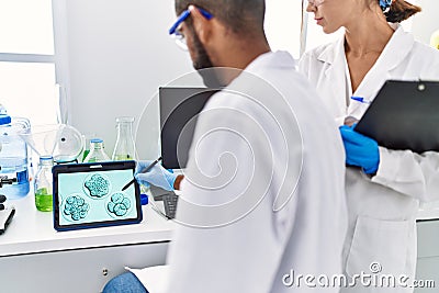 Man and woman scientist partners looking embryo image on touchpad at laboratory Stock Photo