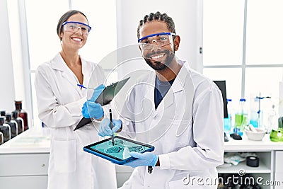 Man and woman scientist partners looking embryo image on touchpad at laboratory Stock Photo