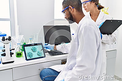 Man and woman scientist partners looking embryo image on touchpad at laboratory Stock Photo