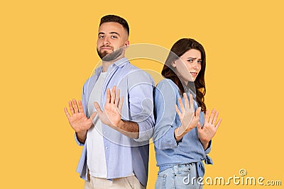 Couple gesturing stop with hands, standoffish poses, yellow background Stock Photo