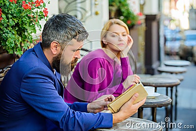 Man and woman sit cafe terrace. Girl interested what he reading. Literature common interest. How to find girlfriend with Stock Photo