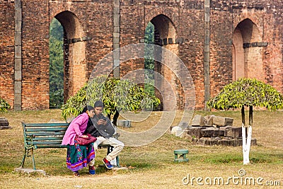 A man and a woman sitting on a bench in the gardens of the ruins of the ancient Adina Editorial Stock Photo