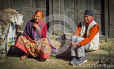 Man and woman sitting on the curb watching people go by, Bhaktapur, Nepal Editorial Stock Photo
