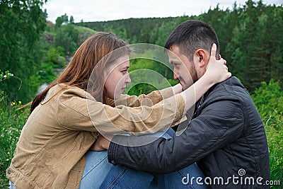 A man and a woman are sitting on a hill facing each other Stock Photo