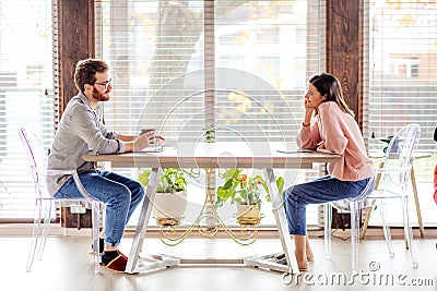 A man and a woman are sitting at a table opposite each other. Stock Photo