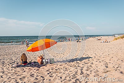 Man and woman sitting under an umbrella on the beach Editorial Stock Photo