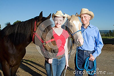 Man and Woman Stand With Horses - horizontal Stock Photo