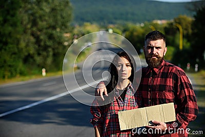 Man and woman try to stop car with cardboard sign. Stock Photo