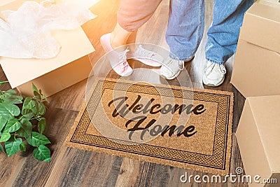 Man and Woman Unpacking Near Welcome Home Welcome Mat, Moving Boxes and Plant Stock Photo