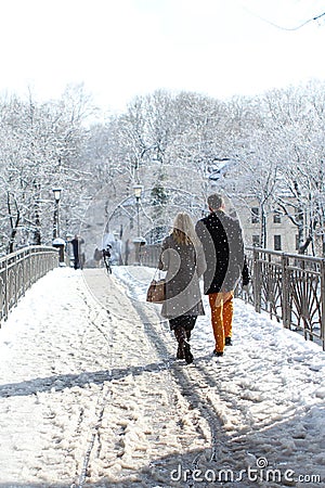 Man and woman walk along the bridge together among the cold white landscape of the city of Munich in the snow, a park in winter, Editorial Stock Photo